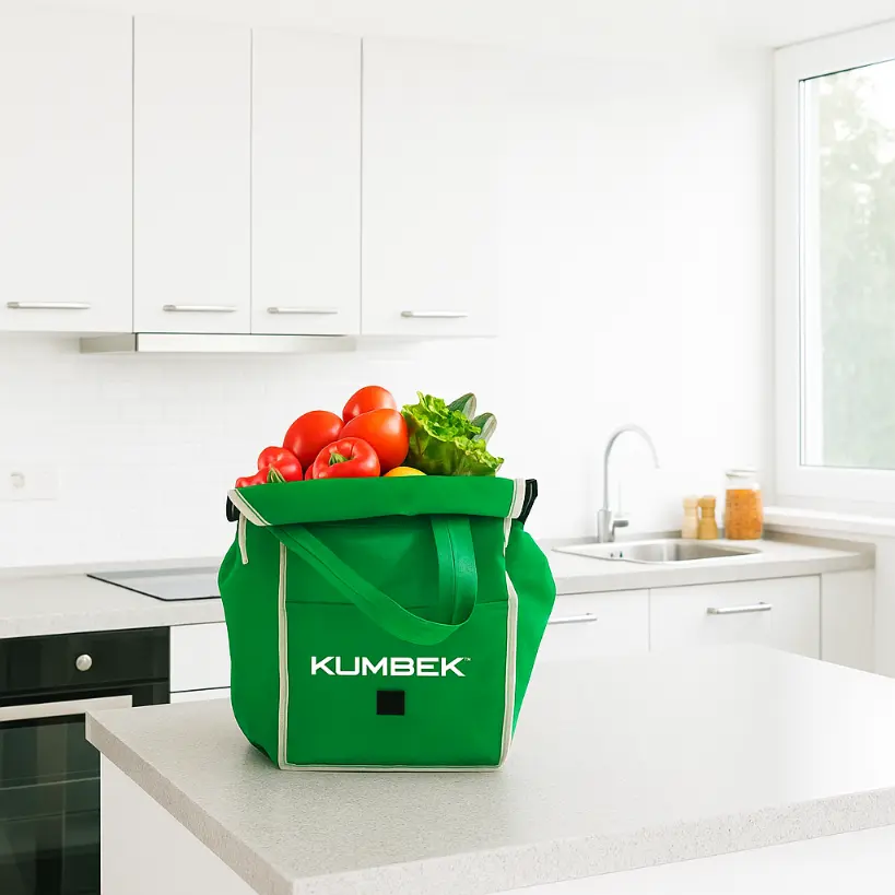 Bolsa carrito supermercado ecológica KUMBEK sobre encimera de cocina llena de verduras y pan, ideal para compras